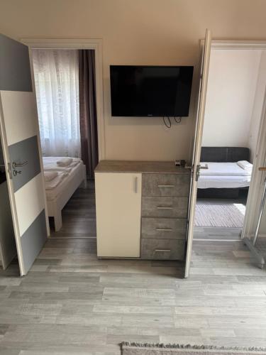 a room with a tv on a wall with a bathroom at Mineral Rubin apartman in Sóstófürdő