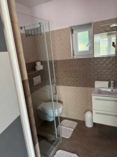 a bathroom with a toilet and a glass shower at Mineral Rubin apartman in Sóstófürdő