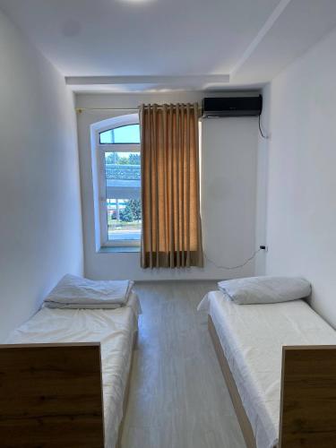two beds in a room with a window at Magnato Hostel in Andizhan