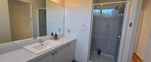 a bathroom with a sink and a shower with a mirror at The 20th Hole in Point Lonsdale