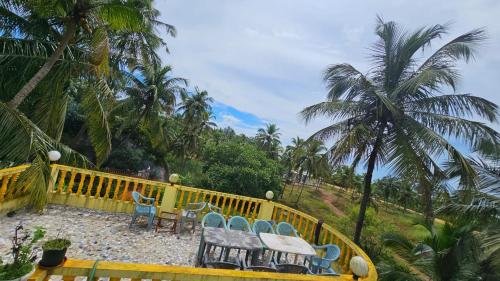 a patio with chairs and tables and palm trees at Flobestian's Seafront Villa in Candolim