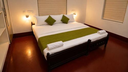 a bedroom with a large bed with green and white pillows at Canorix Inn in Athirappilly