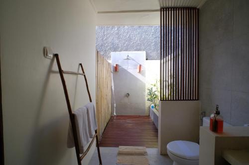 a bathroom with a toilet and a hallway with a staircase at KU Villas in Kuta Lombok