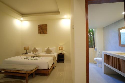 a bedroom with two beds and a bathroom at KU Villas in Kuta Lombok