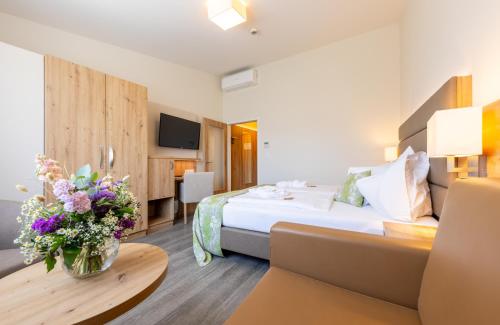 a hotel room with a bed and a table with flowers at Hotel Grimmingblick GesmbH in Bad Mitterndorf