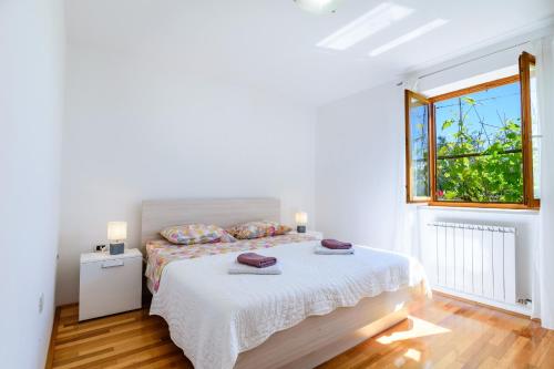 a white bedroom with a bed and a window at Miren apartma Ankaran SP - Peaceful Apartment Ankaran SP in Ankaran
