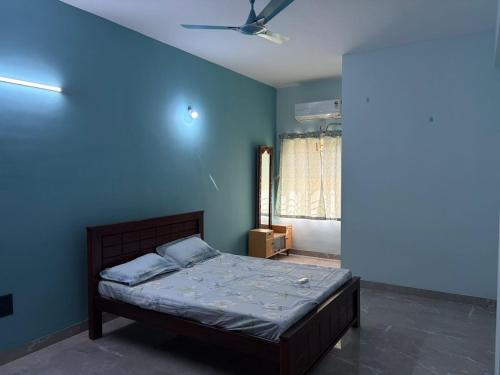 a bedroom with a bed with a blue wall at Chandran Apartments in Vellore
