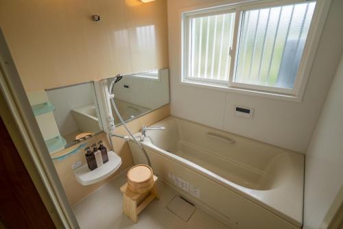 a bathroom with a tub and a toilet and a sink at The Whale House 日光 by Silver Daisy in Nikko