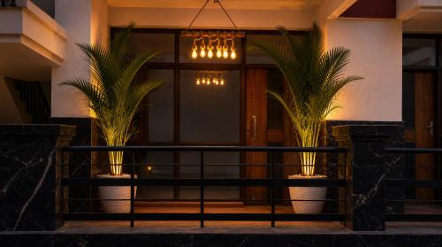 a front porch with two palm trees and a chandelier at Riwaayat & Wings, a luxe stay 5 min from Taj Mahal in Tājganj