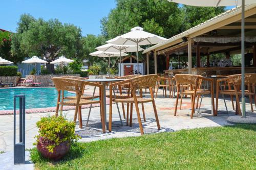 a group of tables and chairs with umbrellas next to a pool at Nikiforos Village in Hanioti