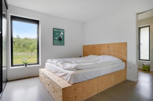 a bedroom with a bed with a wooden headboard and a window at Lübker Golf Resort in Nimtofte