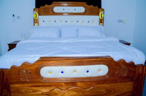 a wooden bed with white sheets and a wooden headboard at Ray Infinity Suites in Paje