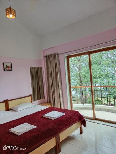 a bedroom with a bed and a large window at Nature Trinity House in Panchgani