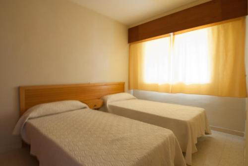 ガンディアにあるApartamentos Marblau Los Iris- Julio y Agosto SOLO FAMILIASのベッド2台と窓が備わる客室です。
