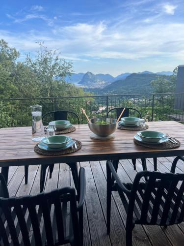 a wooden table with plates and a bowl on it at Casa Cristina - Stunning Lake & Mountain View in Roveredo Capriasca