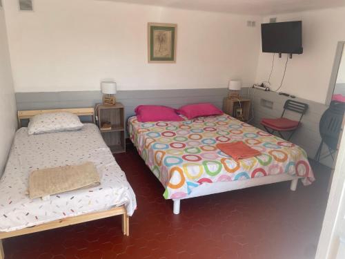 a bedroom with two beds and a flat screen tv at La farigoulette in Rayol-Canadel-sur-Mer