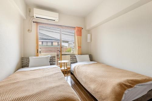 two beds in a room with a window at 大濠ウエストビレッジ209 in Fukuoka