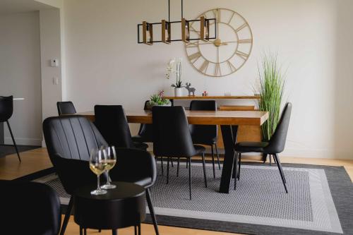 a dining room with a table and chairs and a clock at Elegant Condo - Balcony Pool & Stunning View in Baie-Saint-Paul