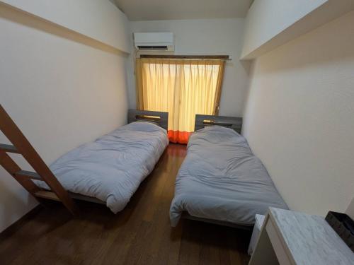 two beds in a small room with a window at 大濠ウエストヴィレッジ409 in Fukuoka