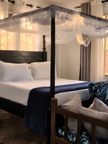 a bedroom with a bed with a canopy at Kilifi Tulivu in Kilifi