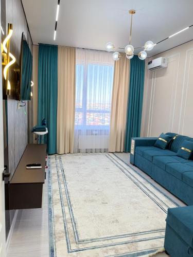 a living room with a blue couch and a large window at Улы Дала in Shymkent