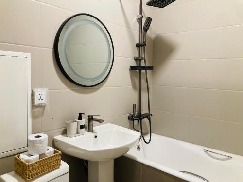a bathroom with a sink and a mirror and a tub at Newly Renovated Japandi 1BR Near Shangri-La in Ulaanbaatar