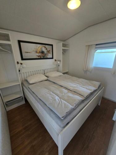 a bedroom with a large white bed in a room at Chalet Ankerplatz in Lauwersoog in Lauwersoog
