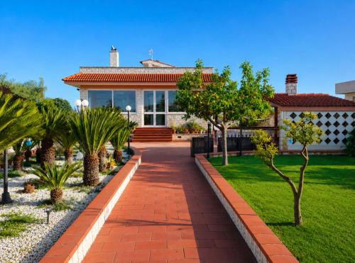 a house with a brick walkway in front of a yard at Villa Daisy Conversano-Polignano a Mare in Conversano