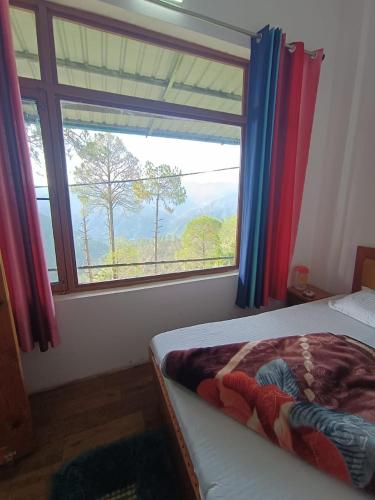 a bedroom with a bed and a window with a view at Bhandari Cottages in Dhanaulti