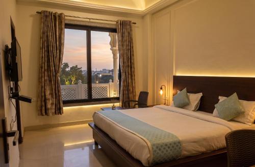 a bedroom with a bed and a window with a view at Jeenmount Heritage Boutique Hotel-JLN Marg in Jaipur