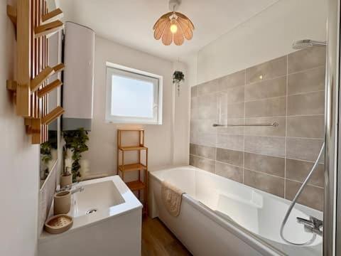 a white bathroom with a tub and a sink at Le Cocon Doré in Calais
