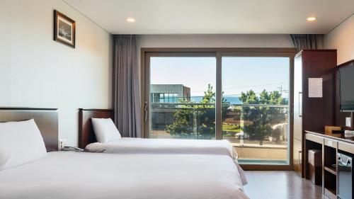 two beds in a hotel room with a large window at 씨뷰 호텔 in Naedo-dong