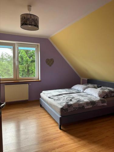 ein Schlafzimmer mit einem Bett und einer lila Wand in der Unterkunft Dom z Basenem i Sauną IKA in Biskupiec