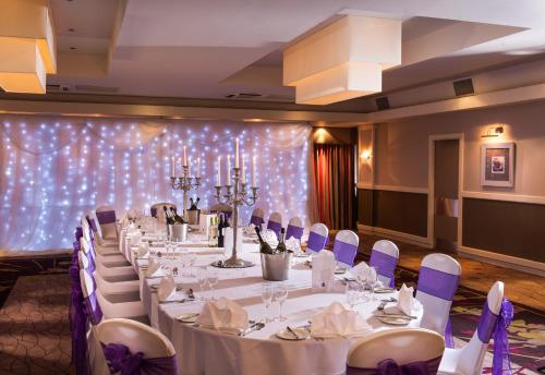 a banquet room with white tables and purple chairs at Leonardo Inn Glasgow West End in Glasgow