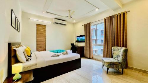 a bedroom with a bed and a chair and a window at BluO Lake View Studio - NewTown - Terrace Garden in Kolkata