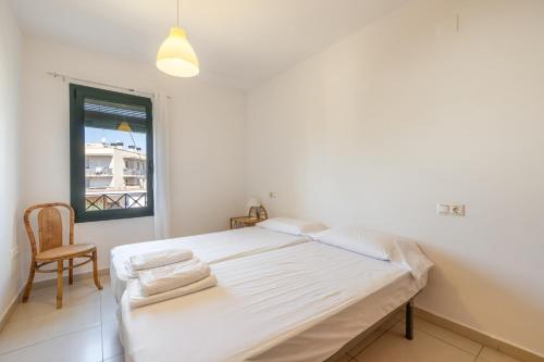 a white bedroom with a bed and a chair at Torredembarra in Torredembarra