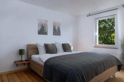 a white bedroom with a large bed and a window at Gemütliches Ferienhaus in Kell am Traumpfad nahe Maria Laach in Andernach