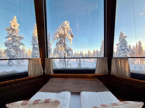a bedroom with a bed and a view of snow covered trees at Nivunki Village in Muonio