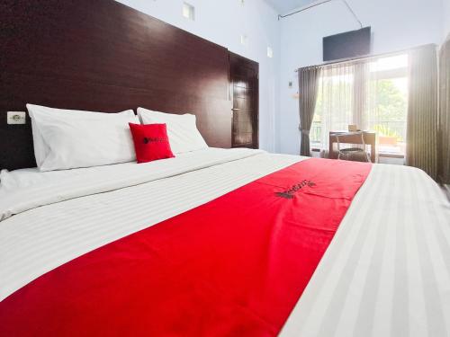 a bedroom with a large bed with a red blanket at RedDoorz near Ramayana Mall Banyuwangi in Banyuwangi