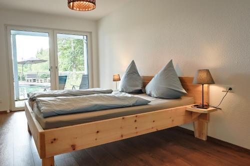 a bedroom with a wooden bed with pillows and a window at Ferienwohnung Bodensee in Meßkirch