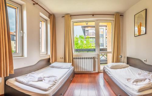 two beds in a room with two windows at Hotel Bojur & Bojurland Apartment Complex in Bansko