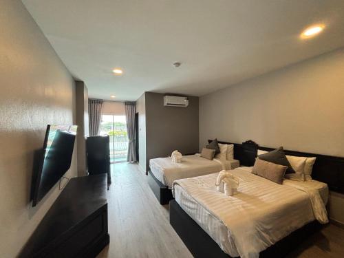 a hotel room with two beds and a tv at Hotel De Kiang Muang in Chiang Mai