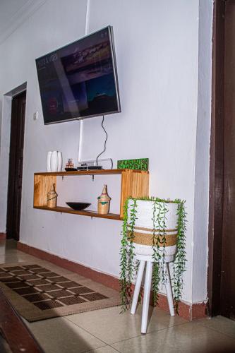 a room with a chair and a tv on a wall at Mbuyu Taifa Greenview Mlandege Apartment in Zanzibar City