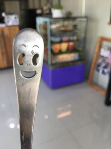a metal spoon with a face on it in front of a refrigerator at The Rhea in Udon Thani