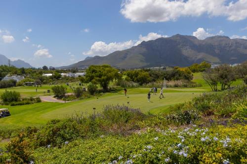 people playing golf on a golf course with mountains in the background at Winelands Golf Lodges 2 in Stellenbosch