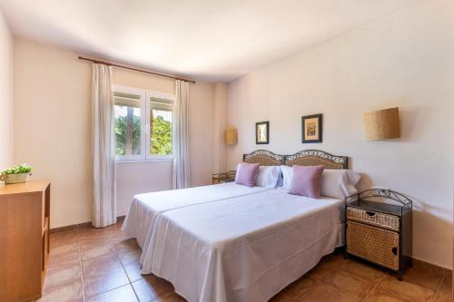a bedroom with a large white bed with pink pillows at Son Bou Pool and Sea in Son Bou