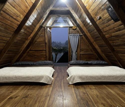 two beds in a attic room with a window at Cozzy Villa Hajeka in Palayangan
