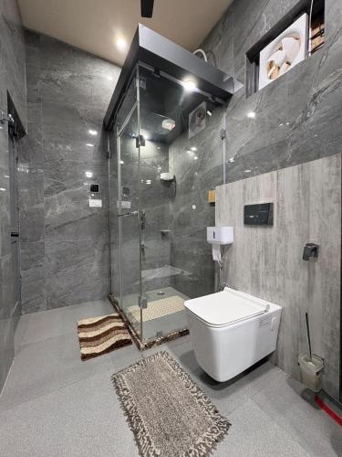 a bathroom with a glass shower and a toilet at Coco Homes Katra in Katra