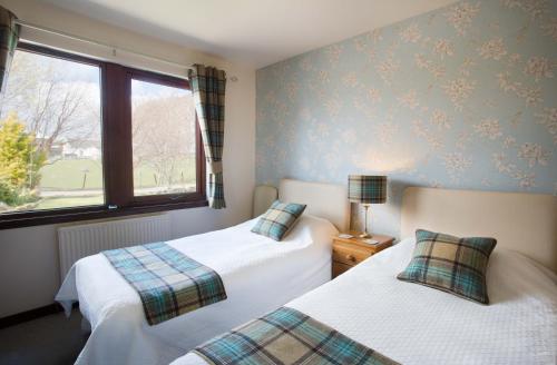 a bedroom with two beds and a window at Leanach Farm in Inverness