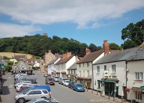 a small town with cars parked on the street at Dunster Castle Hotel in Dunster